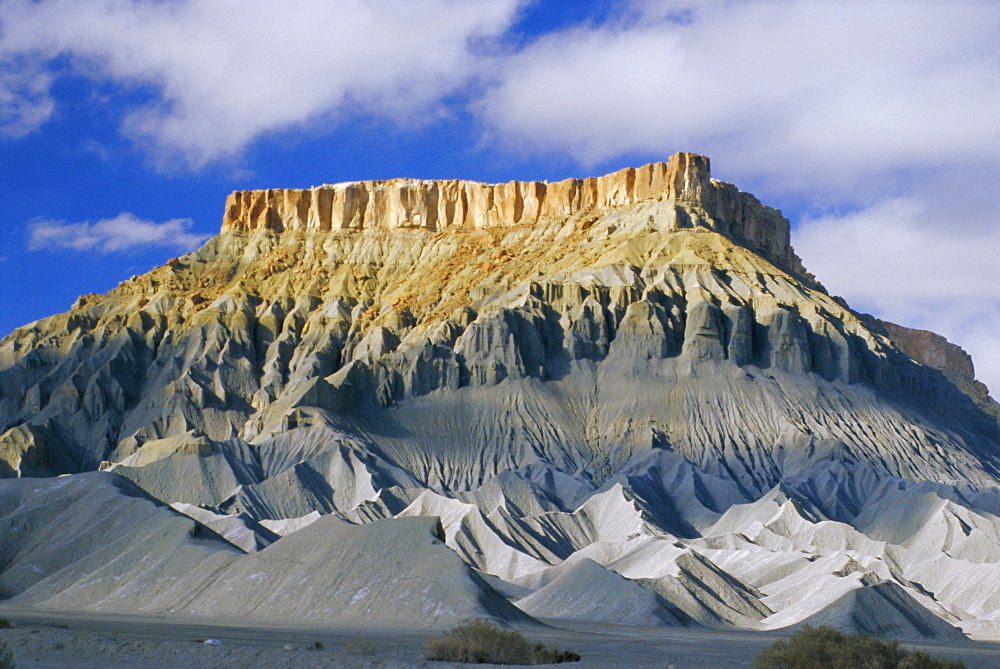 Mesaverde Sandstone cliff over gullied slopes of grey Mancos Shale, resulting from river erosion, Hanksville, Utah, USA