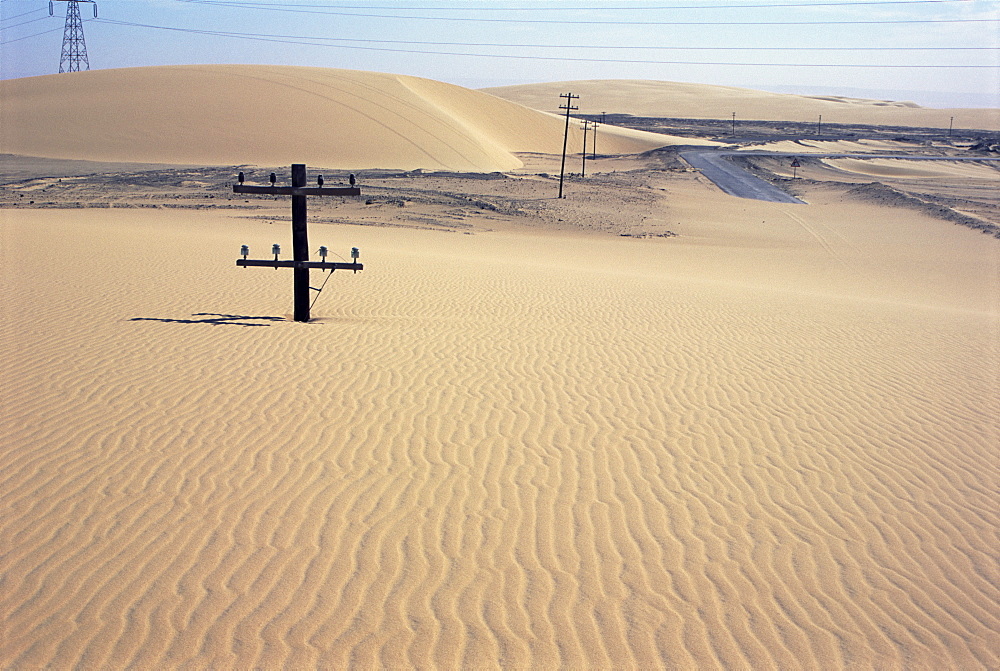 Migrating barchan sand dunes across road marked by buried telegraph poles, Kharga basin, Western Desert, Egypt, North Africa, Africa