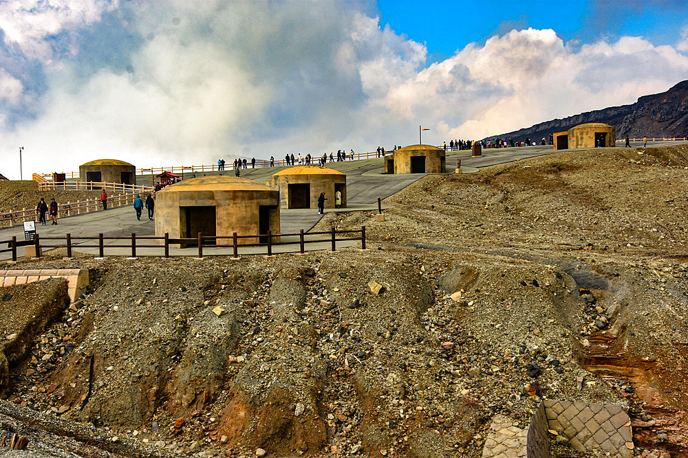 Nakadake volcano within Aso caldera, Kyushu, Japan; bomb shelters for safety during sudden eruptions from steaming crater in background.