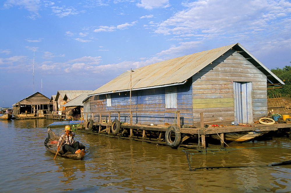 Man in canoe passing a house, floating fishing village of Chong Kneas, Tonle Sap lake, near Siem Reap, Cambodia, Indochina, Southeast Asia, Asia