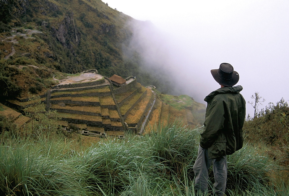 Tourist watches clouds swirl around mountains, Inca Trail, Peru, South America