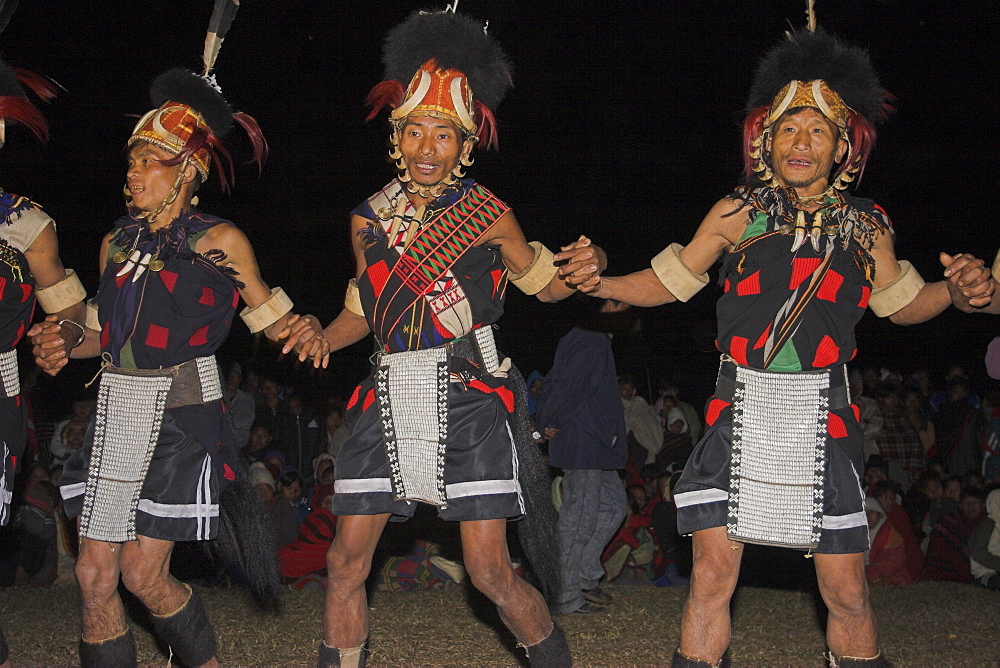 Naga men dancing at Grand Finale wearing headdress made of woven cane decorated with wild boar teeth, bear fur, topped with hornbill feather and tiger claw neckband also tiger teeth necklace, ivory armbands and apron decorated with cowrie shells, Naga New Year Festival, Lahe village, Sagaing Division, Myanmar (Burma), Asia