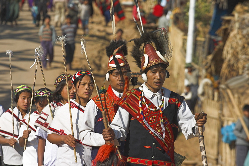 Naga New Year Festival, Naga people walking to festival ground, the men wearing headdress made of woven cane decorated with wildboar teeth, bear fur and topped with hornbill feather also with conch shell ear ornaments, Lahe village, Sagaing Division, Myanmar (Burma), Asia