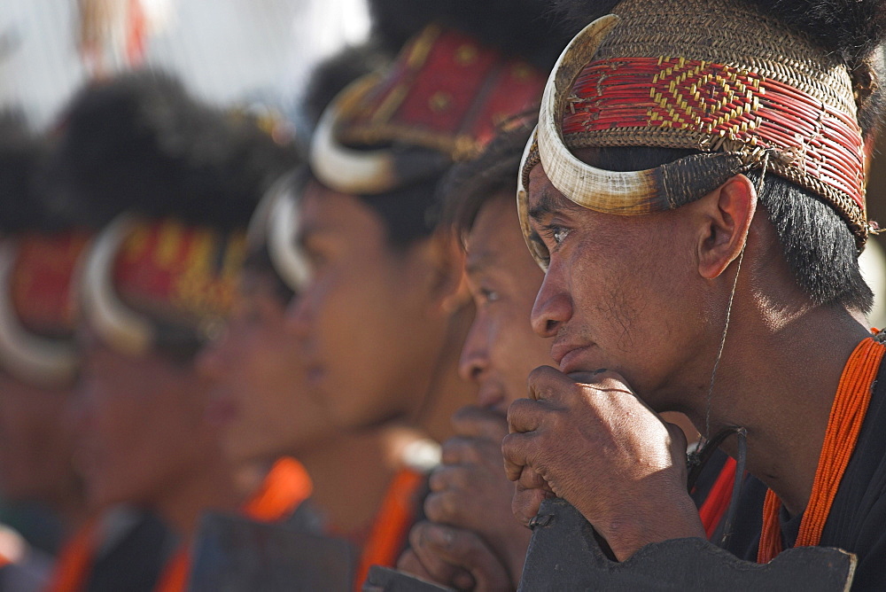 Naga tribes sitting on bench seating whilst the dignitaries make their speeches, they wear headdress made of woven cane decorated with wild boar teeth, and bear fur, Naga New Year Festival,  Lahe village, Sagaing Division, Myanmar (Burma), Asia