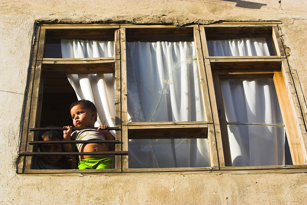 Children looking out of window of old house, Old City, Kabul, Afghanistan, Asia