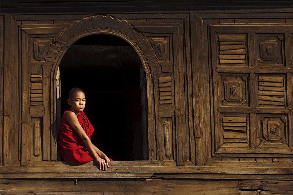 Novice monk sitting in window of 18th century wooden monastery of Nat Taung Kyaung (May-taung taik) thought to be the oldest wooden monastery in the area, Bagan (Pagan), Myanmar (Burma), Asia