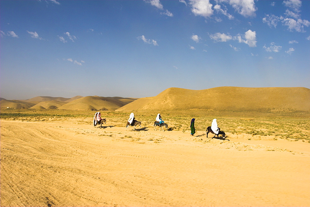 Women ride donkeys along side of road between Maimana and Mazar-I-Sharif, Afghanistan, Asia