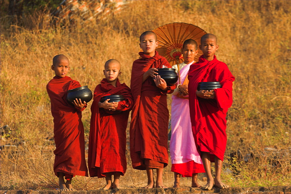 Nun with novice monks holding alms bowls at Mingun Paya, Mingun, Mandalay, Myanmar (Burma), Asia