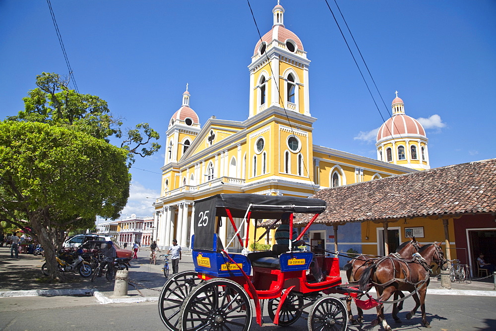 Horse cart passing Cathedral de Granada, Park Colon (Park Central), Granada, Nicaragua, Central America