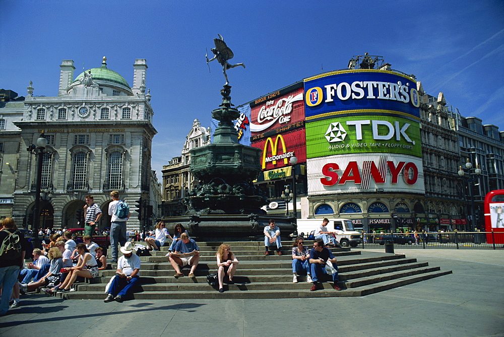 People sitting on steps below the Statue of Eros, Greek God of Love, erected in 1892 in memory of the Earl of Shaftesbury, Piccadilly Circus, London, England, United Kingdom, Europe