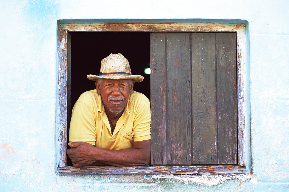 Man leaning out of the window of his house, Trinidad, Cuba, West Indies, Central America