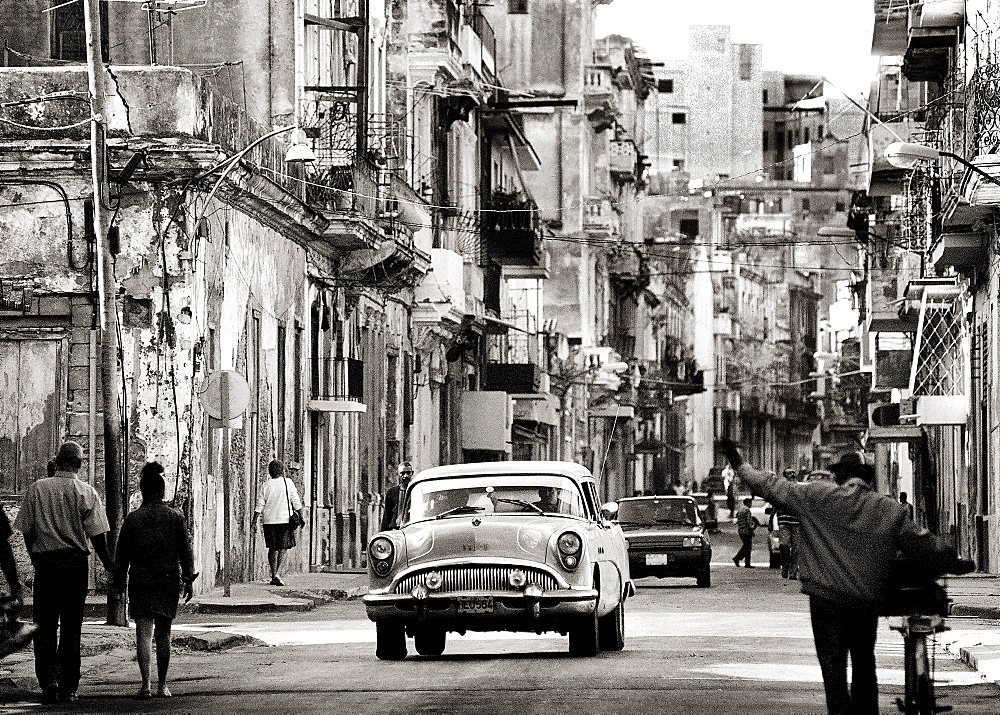 Image taken with a Holga medium format 120 film toy camera of view along busy street showing dilapidated buildings, old American cars and local people, Havana, Cuba, West Indies, Central America