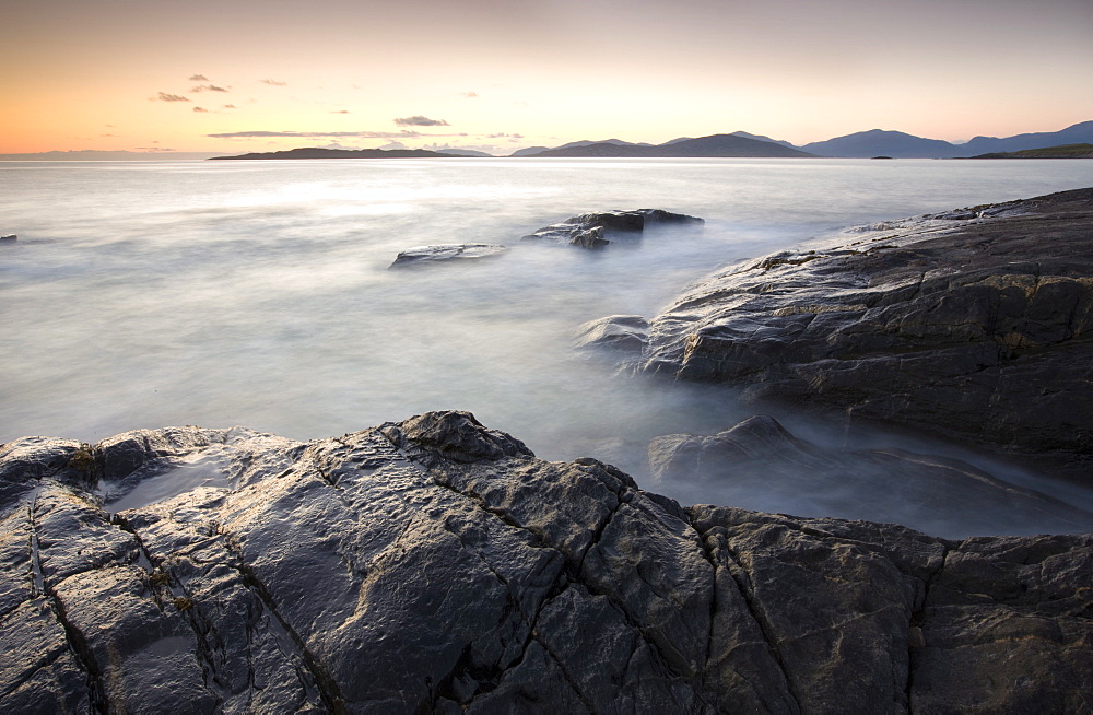 Dusk view across open water towards Taransay and North Harris from the rocky shore at Borve, Isle of Harris, Outer Hebrides, Scotland, United Kingdom, Europe