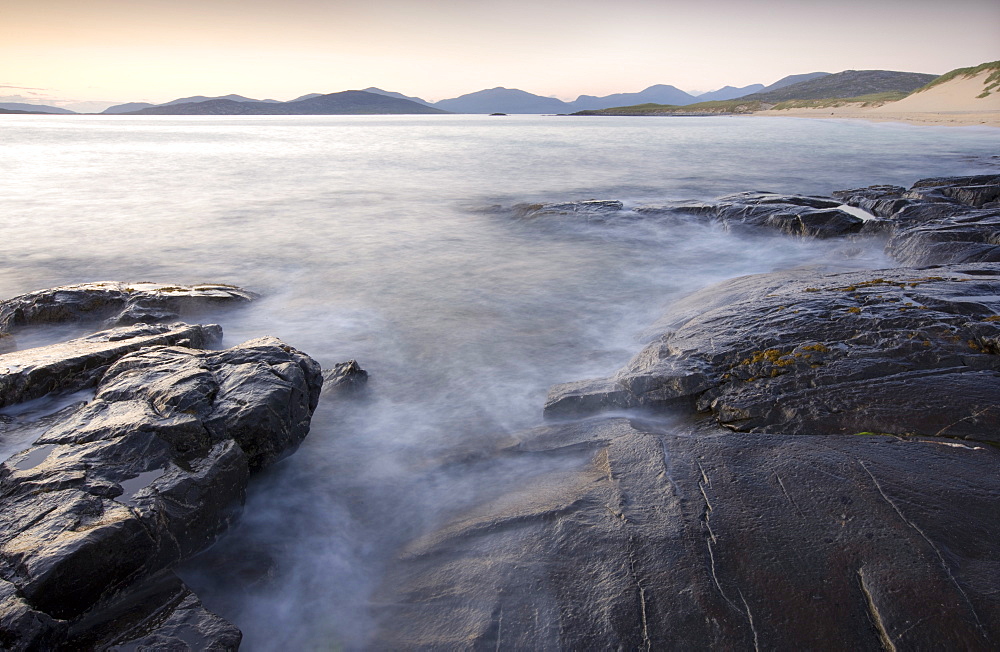 Dusk view across open water towards Taransay and North Harris from the rocky shore at Borve, Isle of Harris, Outer Hebrides, Scotland, United Kingdom, Europe