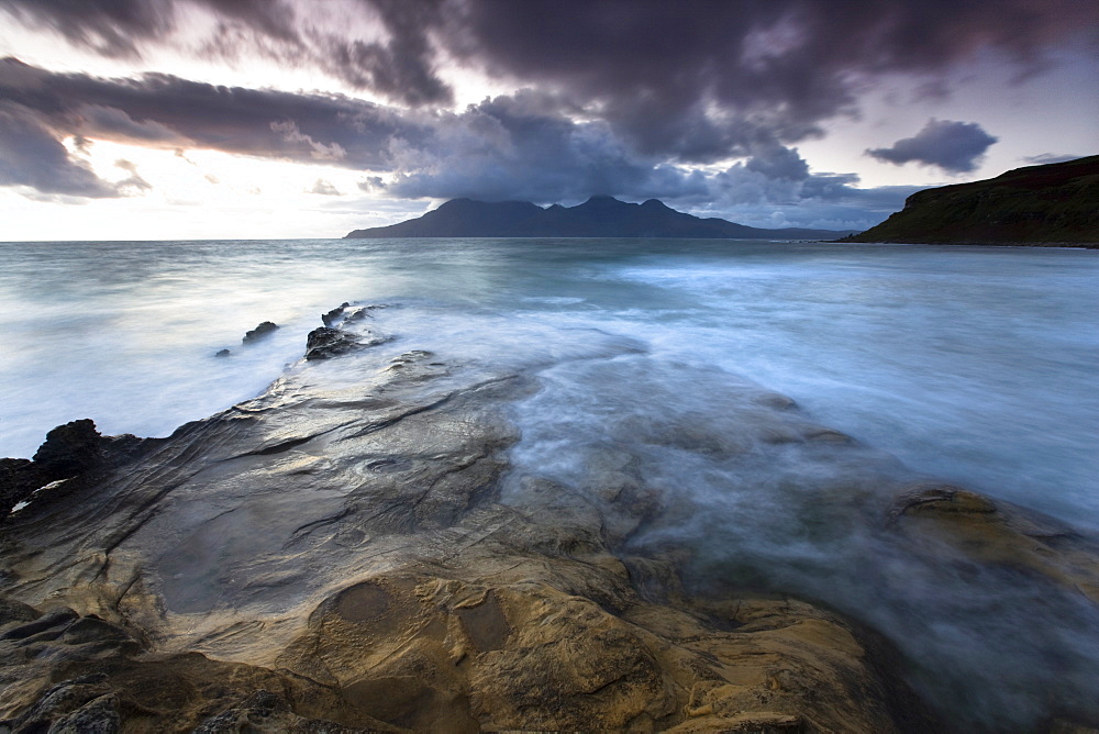 Looking towards Isle of Rum at twilight from rocks at Singing Sands (Camas Sgiotaig), Isle of Eigg, Inner Hebrides, Scotland, United Kingdom, Europe