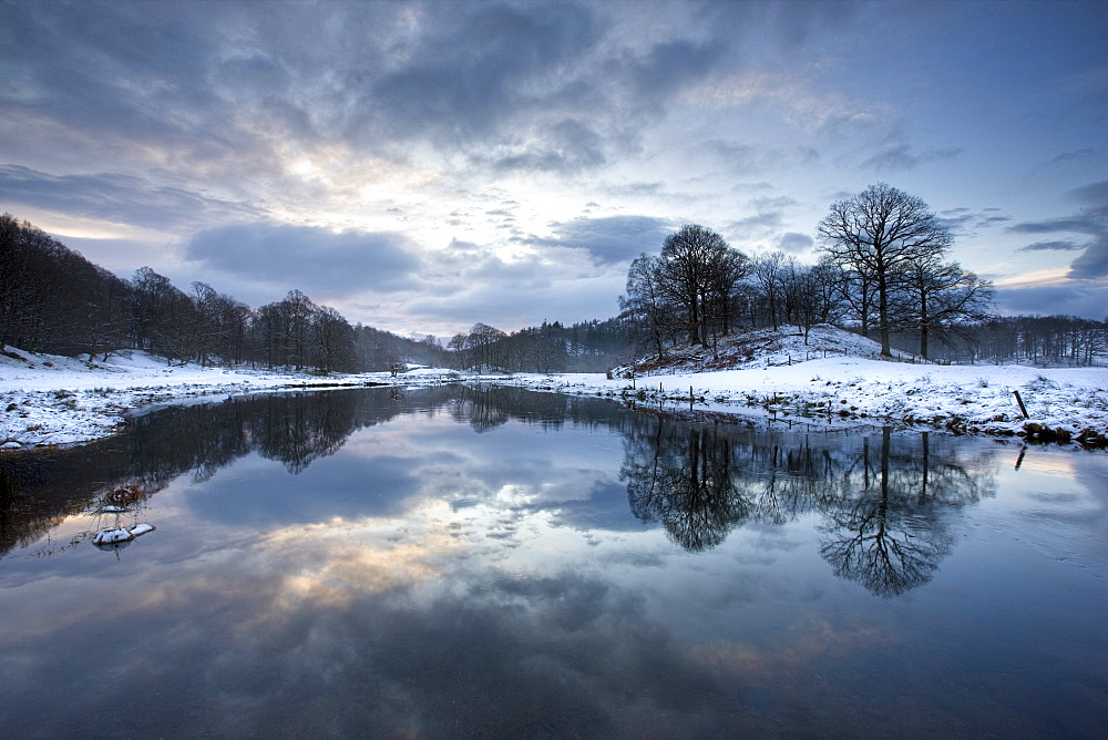 Winter view of River Brathay at dawn, under snow with reflections, near Elterwater Village, Ambleside, Lake District National Park, Cumbria, England, United Kingdom, Europe