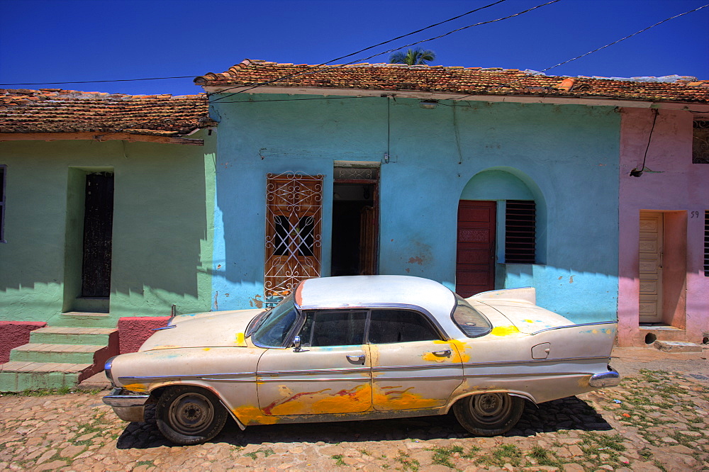 Classic American car parked on cobbled street outside brightly painted houses, Trinidad, Cuba, West Indies, Central America