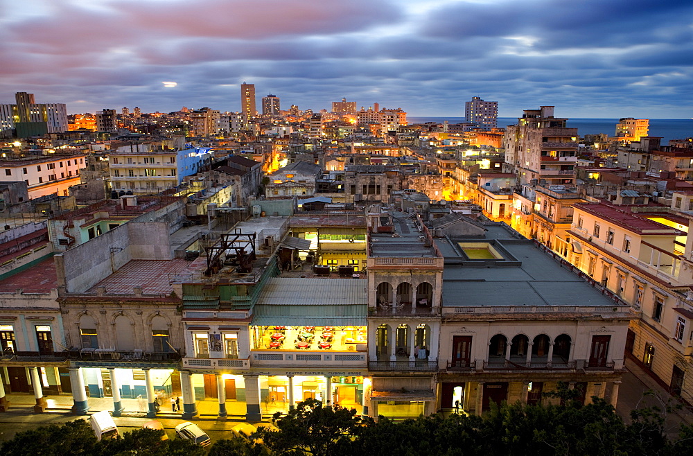 View over Havana Centro at night from 7th floor of Hotel Seville showing contrast of old, semi-derelict apartment buildings against a backdrop of more modern, affluent architecture, Havana, Cuba, West Indies, Central America