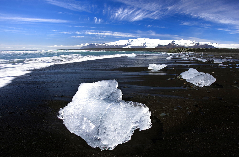 Piece of glacial ice washed ashore by the incoming tide onto beach of volcanic sand near glacial lagoon at Jokulsarlon, Iceland, Polar Regions