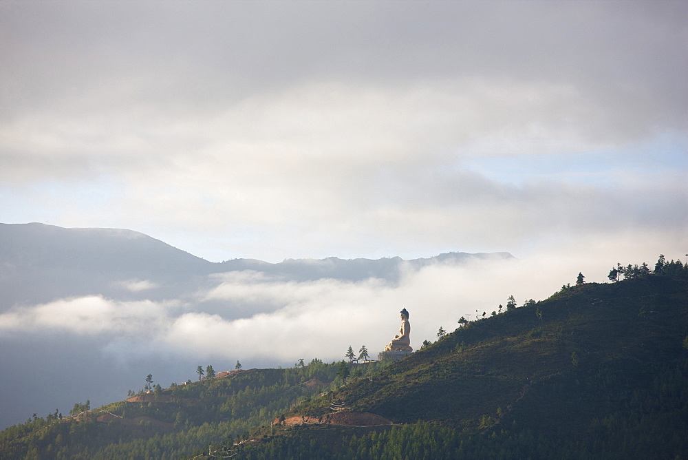 Misty early morning view of giant golden Buddha being constructed on a forested hillside outside Thimpu, Bhutan, Asia