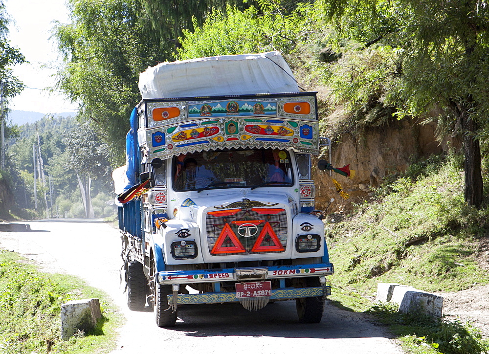 Colourfully decorated truck driving through a village in the Bumthang Valley, Bhutan, Asia