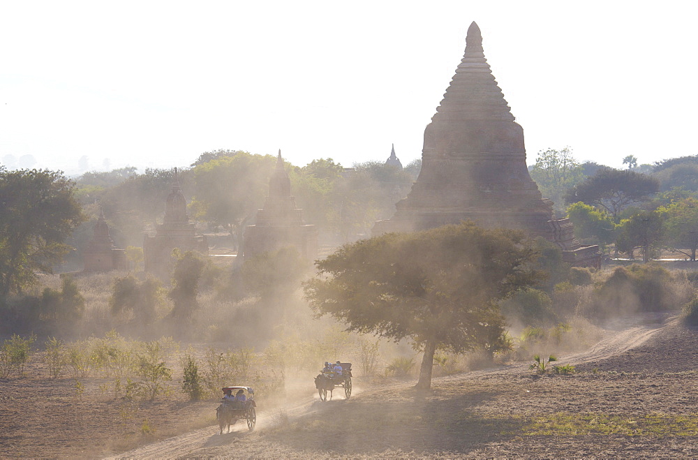 View over the temples of Bagan swathed in evening sunlight with bullock carts travelling along a dusty road, from Shwesandaw Paya, Bagan, Myanmar (Burma), Southeast Asia