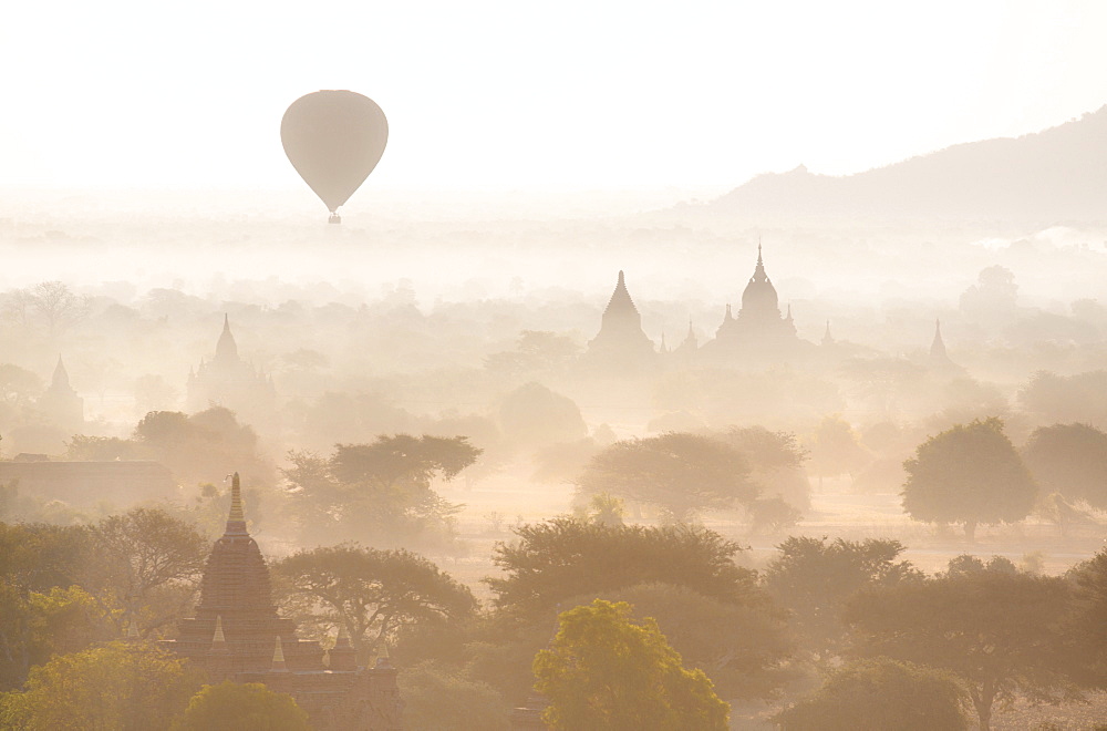 View over the temples of Bagan swathed in early morning mist, with hot air balloon drifting across the scene, from Shwesandaw Paya, Bagan, Myanmar (Burma), Southeast Asia