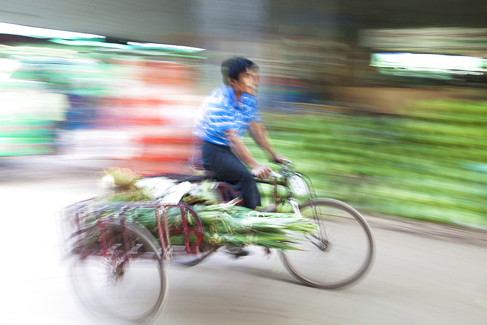 Panned and blurred image to add a sense of movement of a man cycling through Thiri Mingalar market, Yangon (Rangoon), Myanmar (Burma), Asia