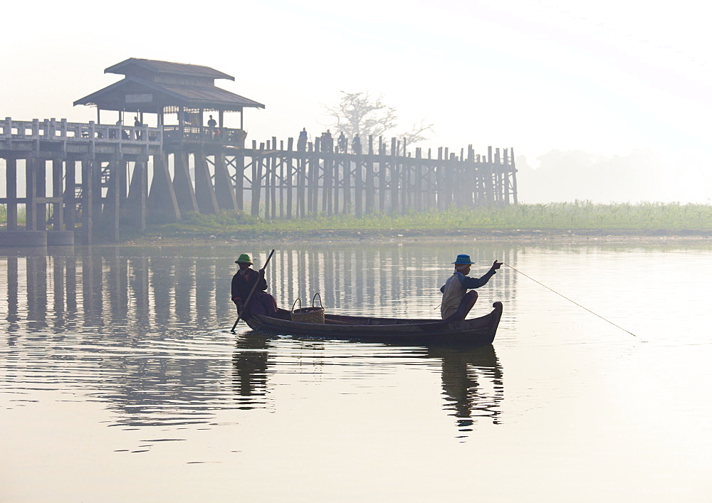 Fisherman on Taungthaman Lake in mist at dawn with U Bein Bridge, the world's longest teak foot bridge spanning 1300 yards, Amarapura, near Mandalay, Myanmar (Burma), Asia