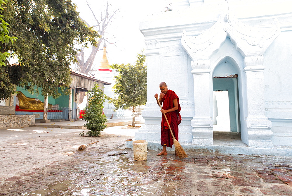 Buddhist monk cleaning paving outside a small temple near the famous U Bein teak bridge, Amarapura, near Mandalay, Myanmar (Burnma), Asia