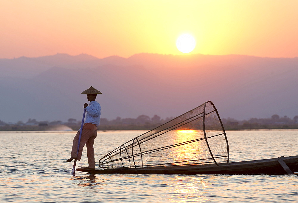 Intha leg rowing fishermen at sunset on Inle Lake who row traditional wooden boats using their leg and fish using nets stretched over conical bamboo frames, Inle Lake, Shan State, Myanmar (Burma), Asia