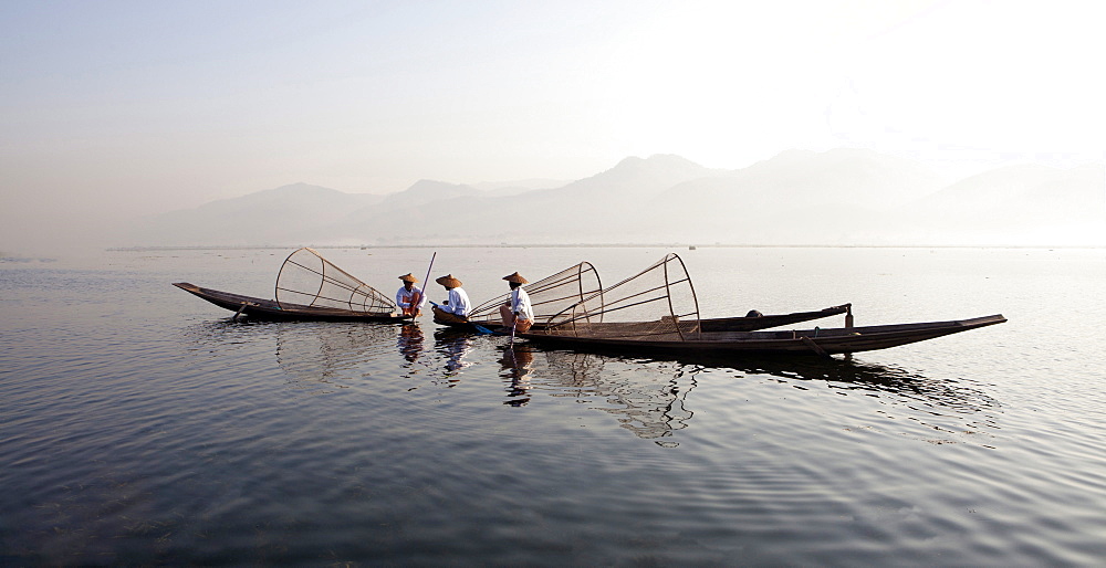 Intha leg rowing fishermen on Inle Lake who row traditional wooden boats using their leg and fish using nets stretched over conical bamboo frames, Inle Lake, Shan State, Myanmar (Burma), Asia