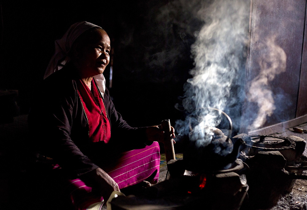 Woman of the Palaung tribe cooking on open fire in her home in village near Kengtung (Kyaingtong), Shan State, Myanmar (Burma), Asia