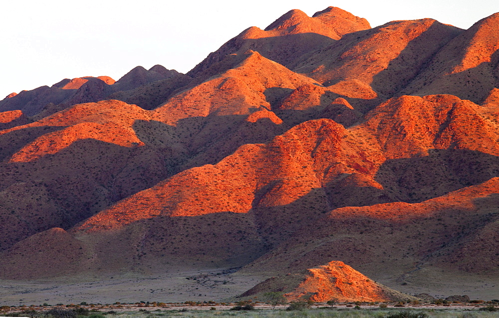 Sandstone mountains lit by the last rays of light from the setting sun, near Sesriem, Namib Desert, Namib Naukluft Park, Namibia, Africa