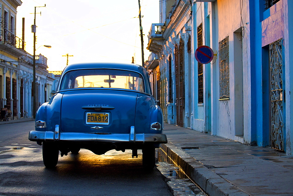 Vintage blue Plymouth American car backlit by the setting sun, Cienfuegos, Cuba, West Indies, Central America