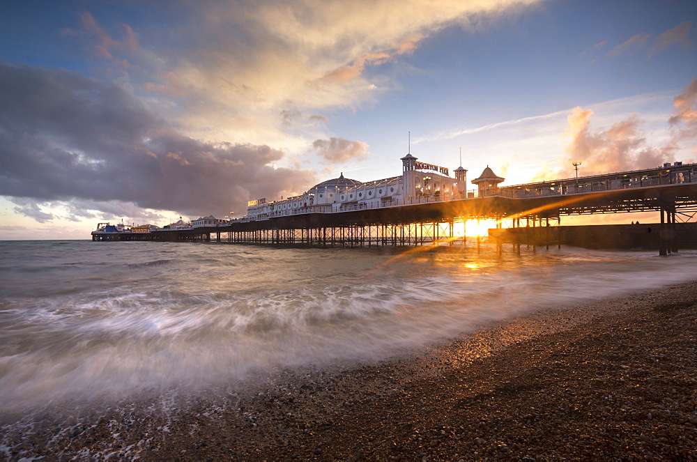 Brighton Pier at sunset with dramatic sky and waves washing up the beach, Brighton, East Sussex, England, United Kingdom, Europe