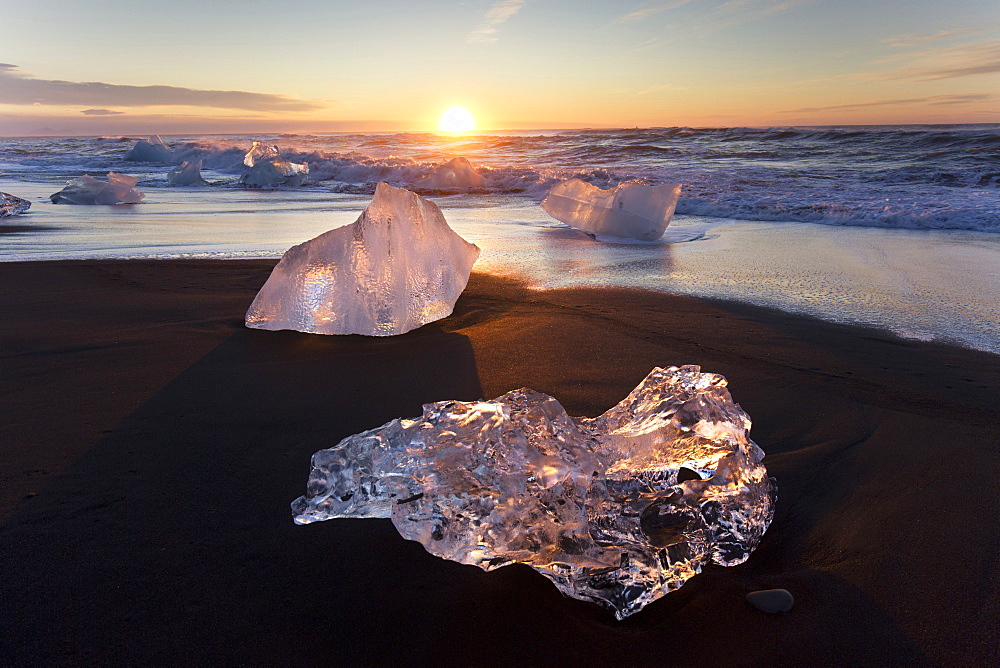 Glassy pieces of ice on volcanic black sand beach at sunrise, near Jokulsarlon Lagoon, South Iceland, Polar Regions