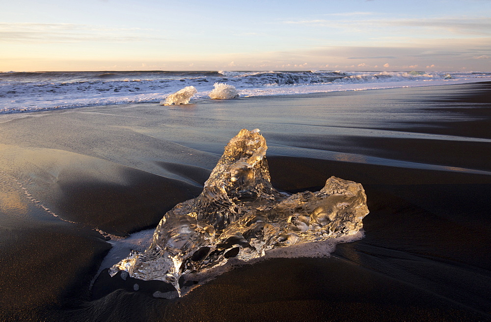 Glassy pieces of ice on volcanic black sand beach at sunrise, near Jokulsarlon Lagoon, South Iceland, Polar Regions