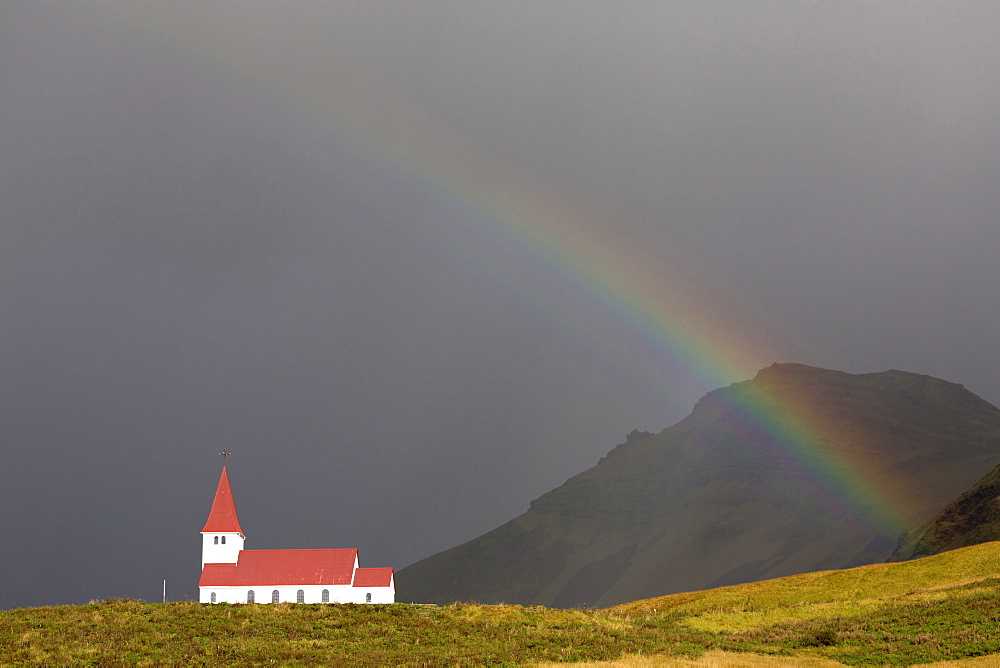 Church and rainbow against stormy sky and mountains, Vik Y Myrdal, South Iceland, Polar Regions