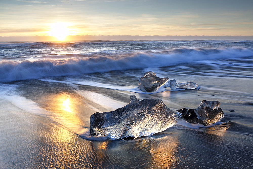 Pieces of glacier ice washed up on black volcanic sand beach at sunrise, near Jokulsarlon Glacial Lagoon, South Iceland, Polar Regions