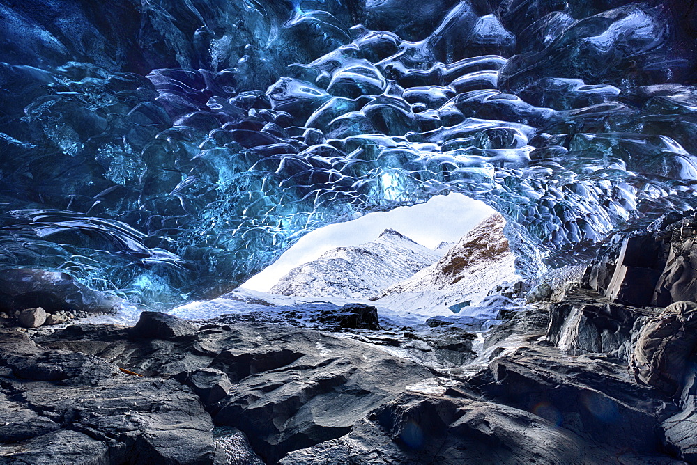 View from inside ice cave under the Vatnajokull Glacier towards snow covered mountains, near Jokulsarlon Lagoon, South Iceland, Polar Regions