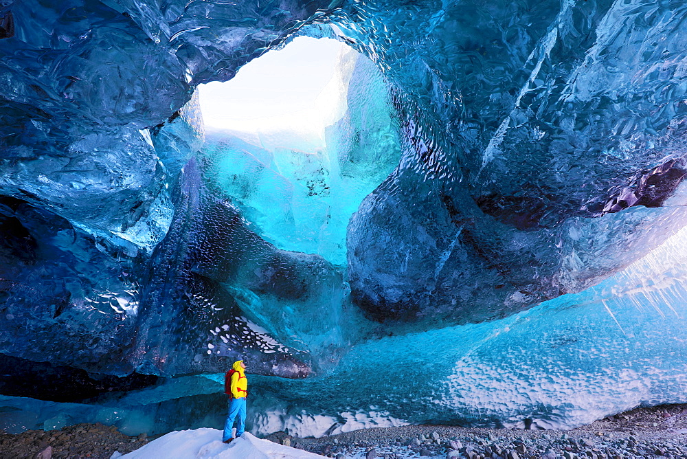 Inside ice cave under the Vatnajokull Glacier, with cave guide looking up to hole in cave roof, near Jokulsarlon, South Iceland, Polar Regions