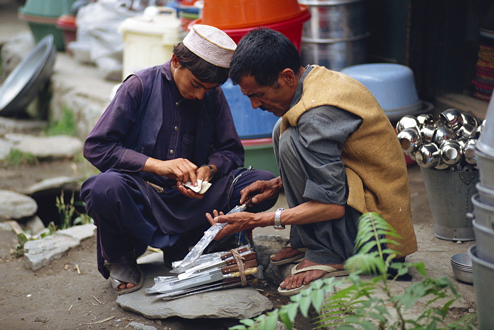 A young man counting his money buying a knife from a street trader in Gilgit, Pakistan, Asia