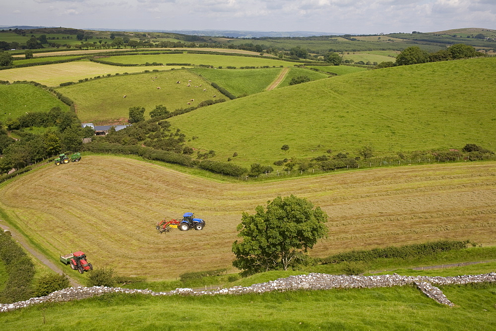 Tractors harvesting in field by Carreg Cennon, Brecon Beacons National Park, Wales, United Kingdom, Europe