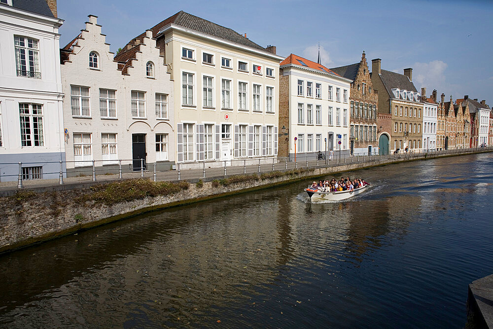 Spinolarei Canal with buildings on Sint-Annarei and approaching boat carrying tourists, Bruges, Belgium, Europe