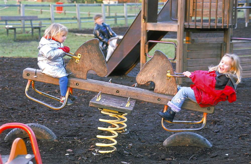 Fair haired sisters playing on a seesaw