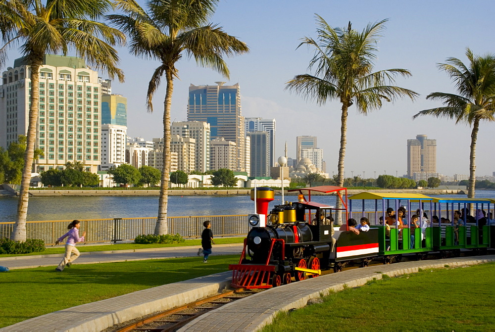 Train in the park, and Sharjah Creek skyline, Sharjah, United Arab Emirates, Middle East