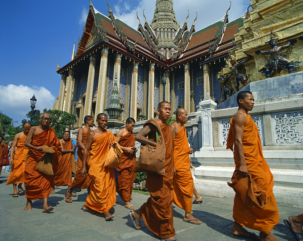 Monks in saffron robes walk past a temple in Bangkok, Thailand, Southeast Asia, Asia