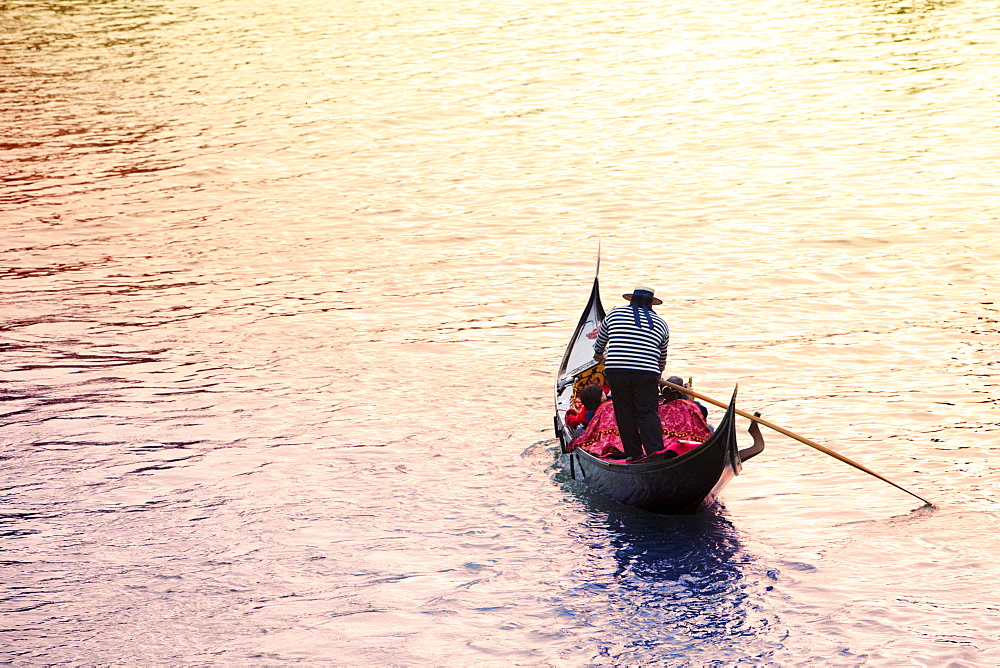 Gondola at sunset carrying passengers across the Grand Canal by St. Marks Square, Venice, Veneto, Italy, Europe