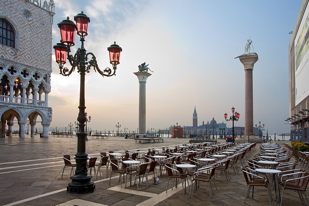 Cafe tables and chairs in the early morning in St. Marks Square, with Isola di San Giorgio Maggiore in distance, Venice, UNESCO World Heritage Site, Veneto, Italy, Europe